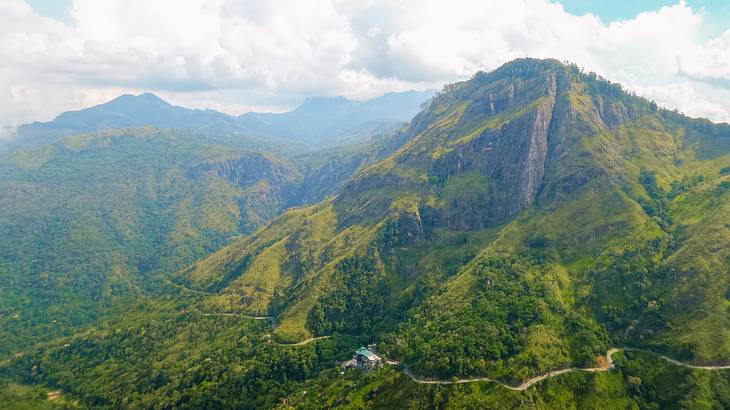 A green mountain range with a road on the valley of one of the mountains