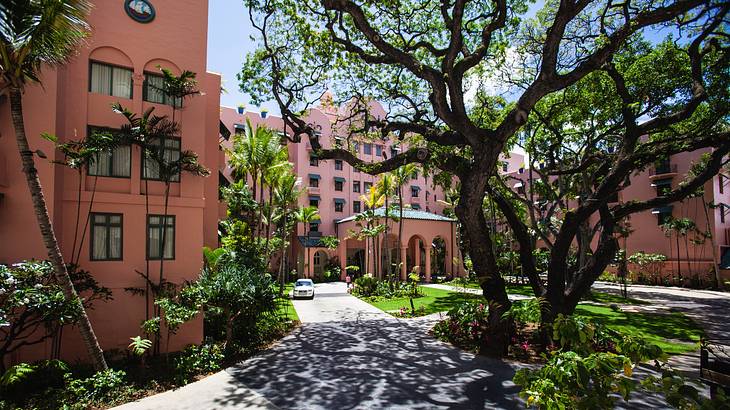 A pink building with a courtyard, and a car parked on a paved road