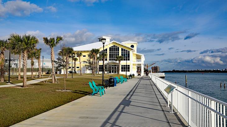 A white and yellow house with a boardwalk in front near a body of water