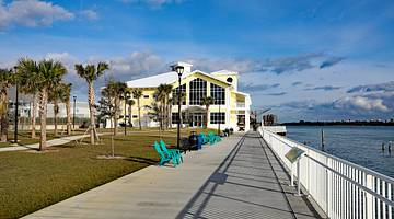 A white and yellow house with a boardwalk in front near a body of water