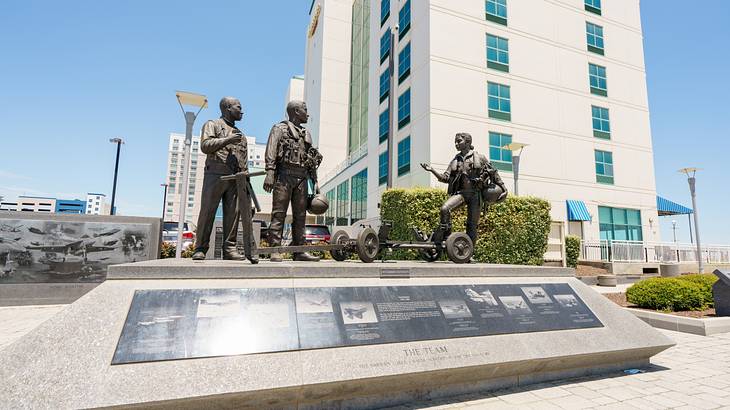Bronze life-sized sculptures of soldiers next to buildings on a sunny day