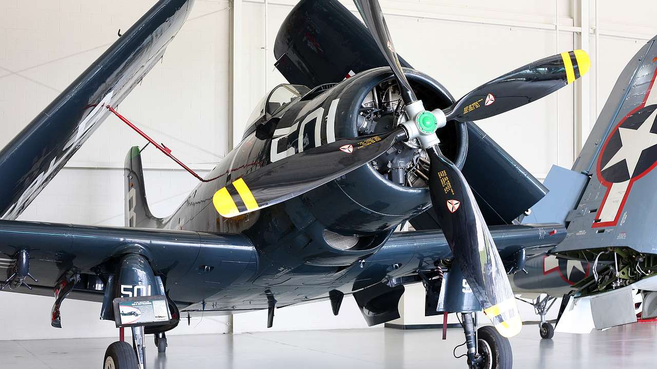 A black propeller plane parked indoors