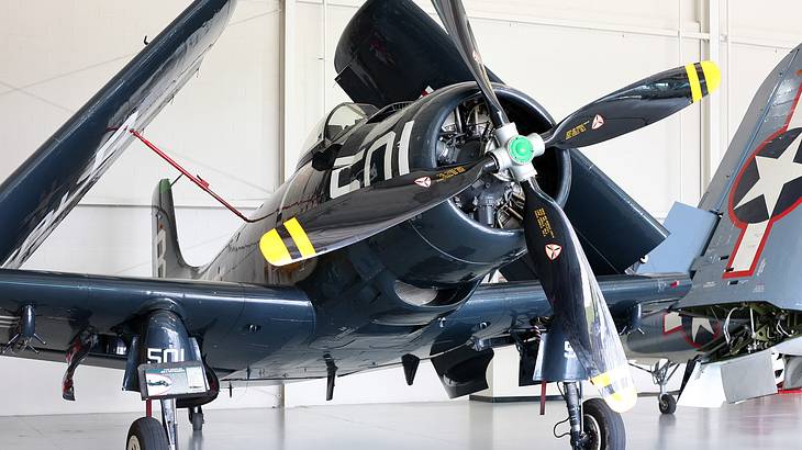 A black propeller plane parked indoors