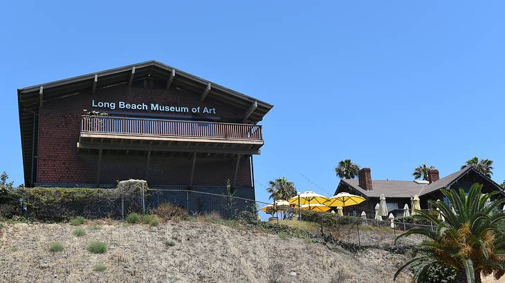 A brick house atop a hill with a "Long Beach Museum of Art" sign on it