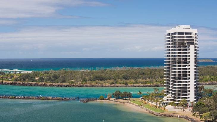 A tall apartment building on the right surrounded by land and water A tall apartment building on the right surrounded by land and water