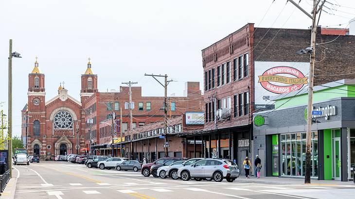 A street with cars, buildings, and a brick cathedral with two towers at the end A street with cars, buildings, and a brick cathedral with two towers at the end