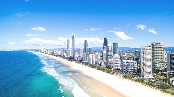 An aerial photo of a stunning city skyline along blue water and white sand