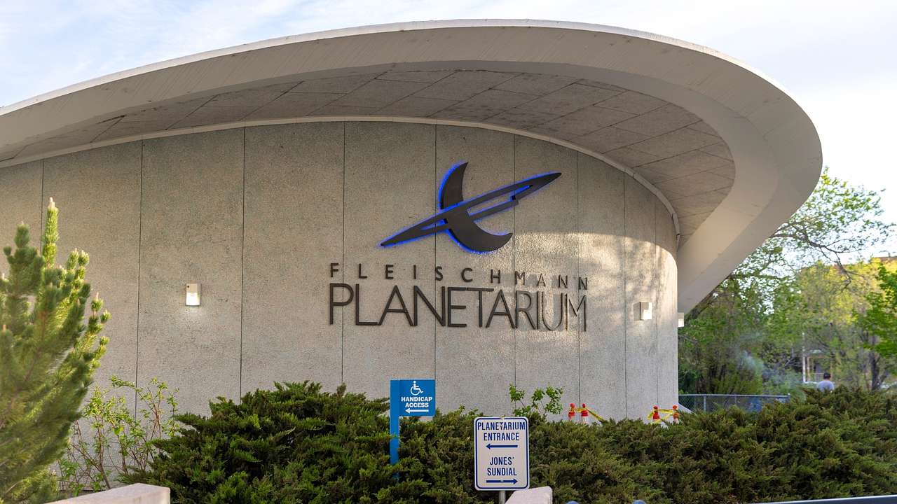 A curved building with a sign that says "Fleischmann Planetarium"