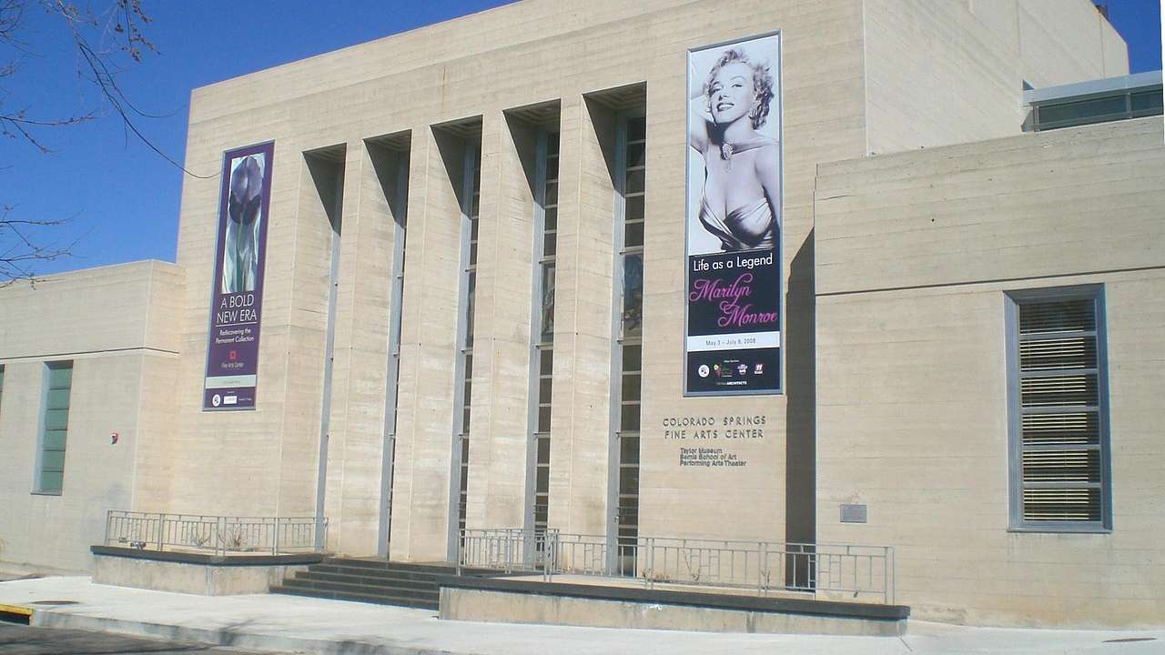 A stone museum building with banners on it under a blue sky