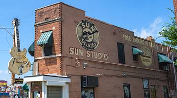 A red brick building with a guitar sculpture and a sign that says "Sun Studio"