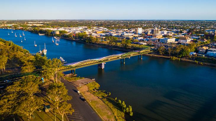 Aerial view of Bundaberg with buildings, cars on a street and boats on a river