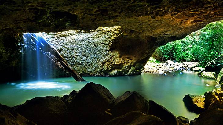 A view from the cave of the Natural Bridge over water with a waterfall A view from the cave of the Natural Bridge over water with a waterfall
