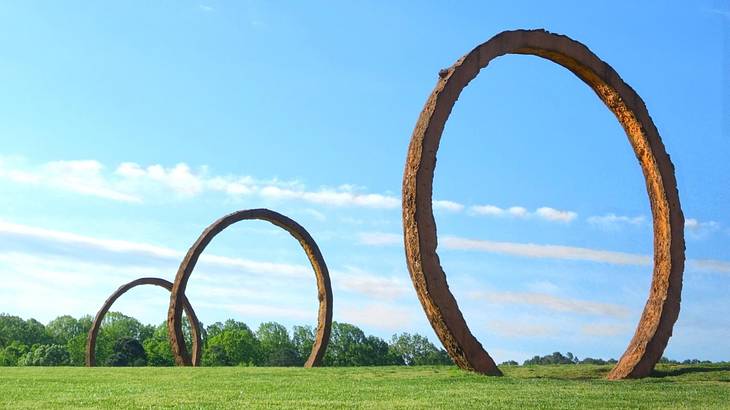 Circle-shaped sculptures on the grass under a blue sky