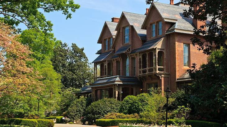 A redbrick house with a green garden in front of it