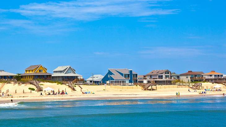 A beach with sandy shores, blue ocean, and beach huts under a blue sky