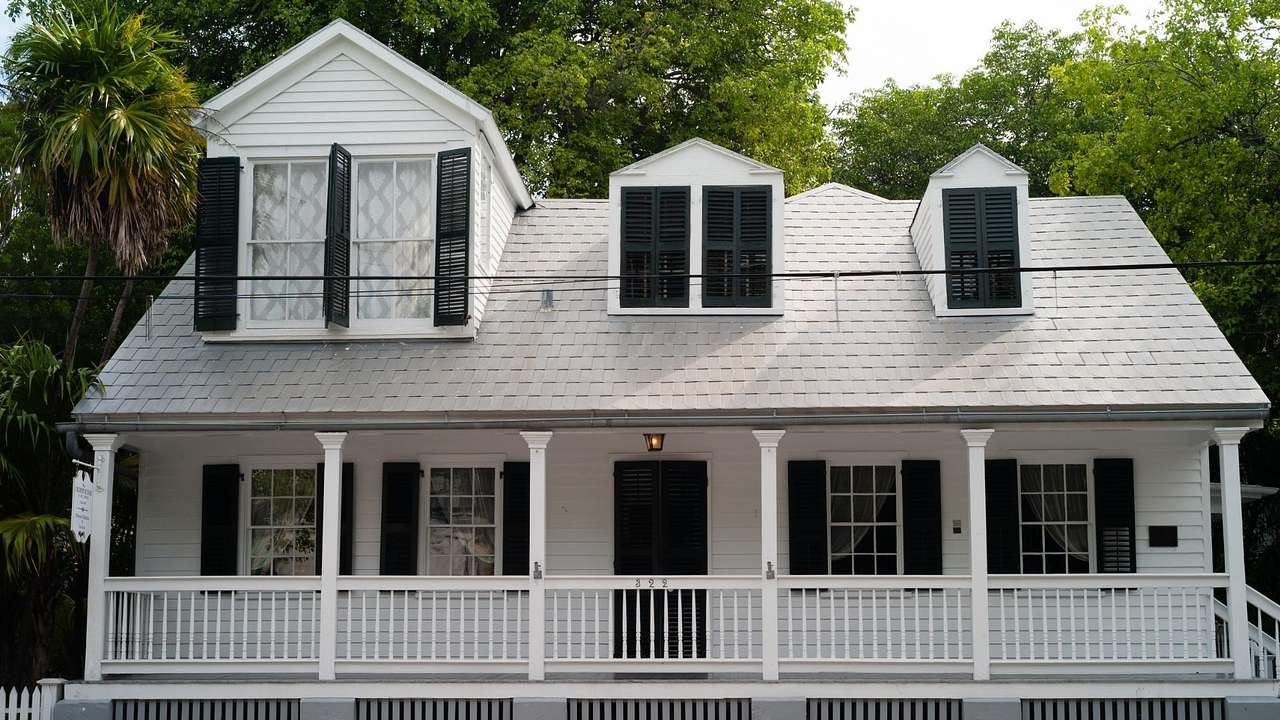 A white house with black window shutters and a porch