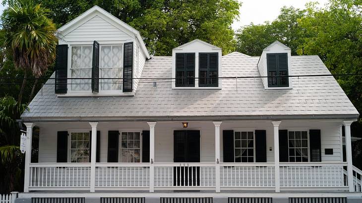 A white house with black window shutters and a porch