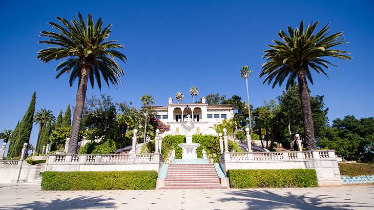 A palace-like white mansion with a front courtyard and steps leading up to the house