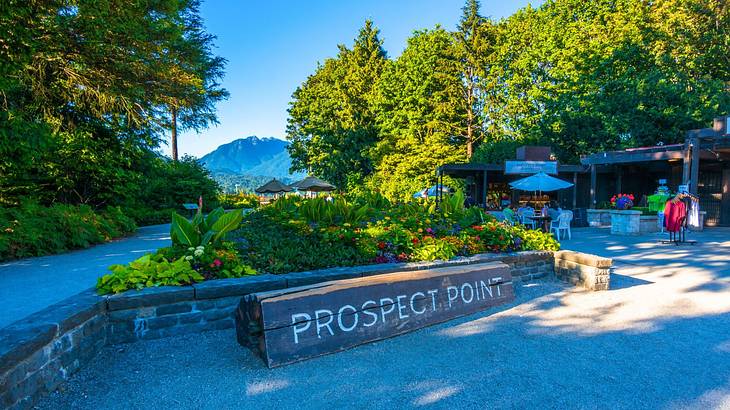 A graveled lot with a log sign next to a cafe, trees, and a mountain in the distance