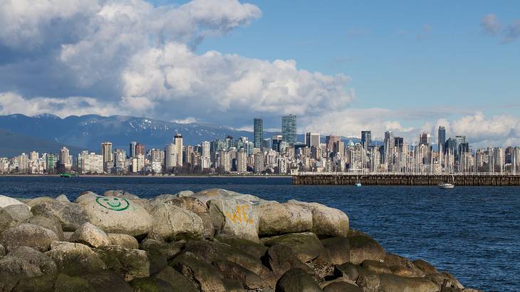 A rocky coast with a view of an urban landscape from across a body of water