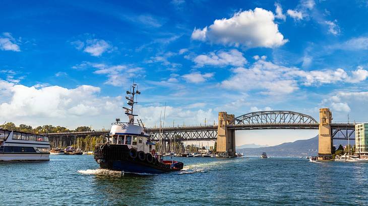 A body of water with a boat on it next to a bridge under a blue sky with clouds