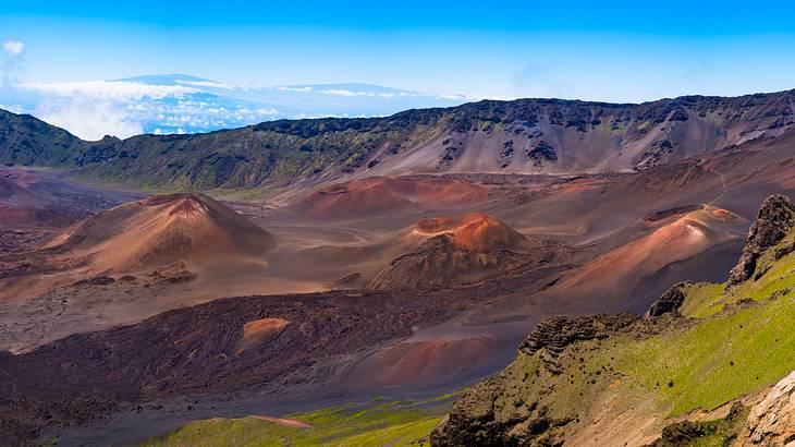 Several reddish volcanic craters surrounded by green mountains