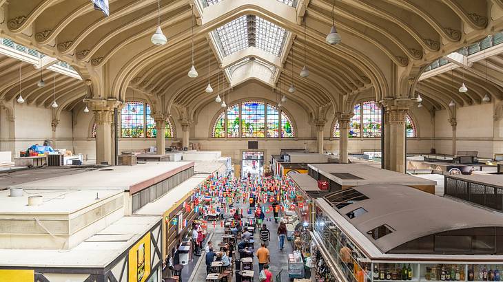 A view over an indoor market with a high arched ceiling and stained glass windows