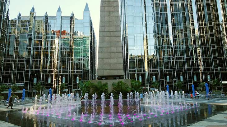 An urban square with a water feature and tall mirrored buildings