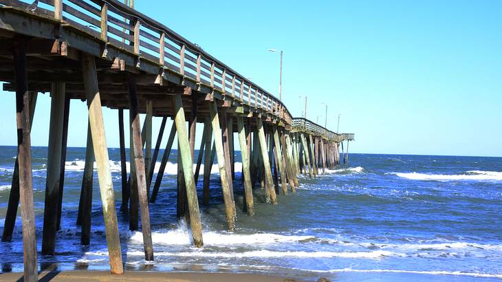 A long wooden pier with the sea and beach sand underneath