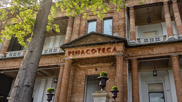 A brick building with an arched doorway that says "Pinacoteca"