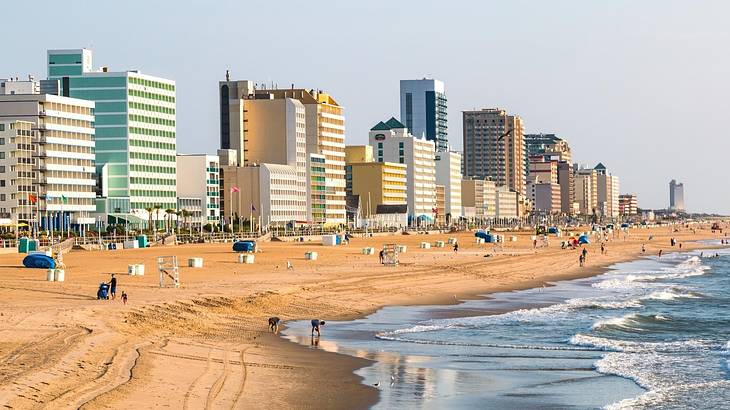 A beach with sandy shores and ocean water next to tall buildings A beach with sandy shores and ocean water next to tall buildings