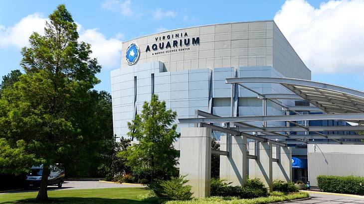 A large building with a Virginia Aquarium sign and grass and trees in front of it