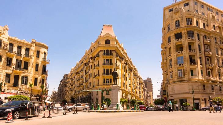 Corner buildings near a road junction and a monument under a blue sky