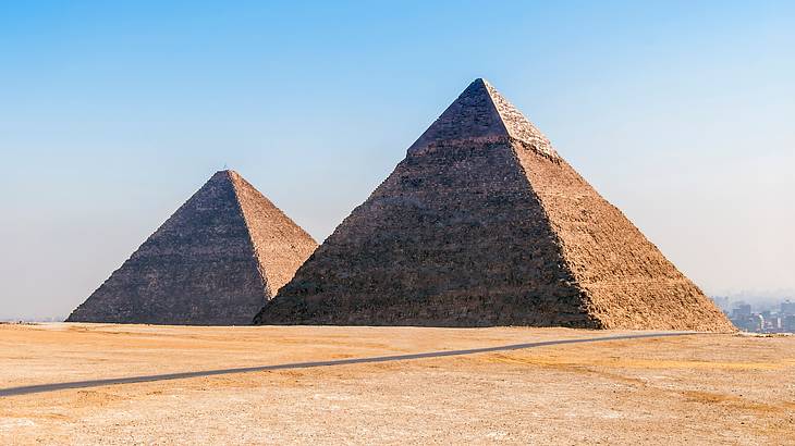 Two pyramids surrounded by sand on a sunny day