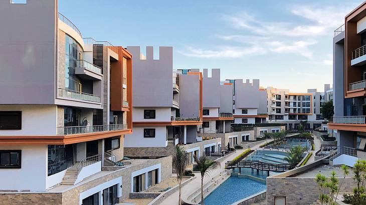 Modernistic buildings near walkways and a pool under a blue sky