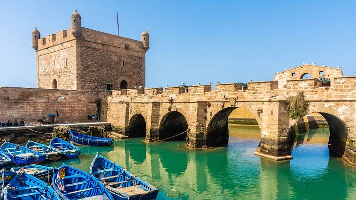 Blue boats docked near a fortress