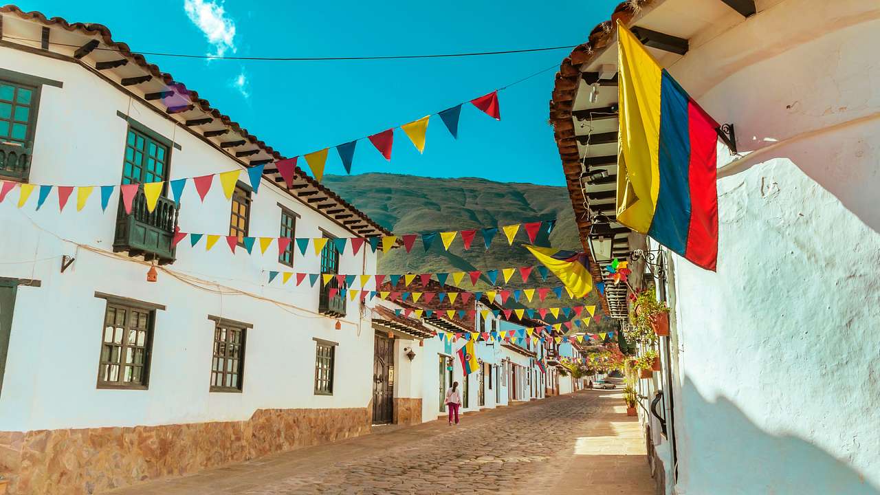 A street decorated with colorful flags and a Colombian flag on a sunny day