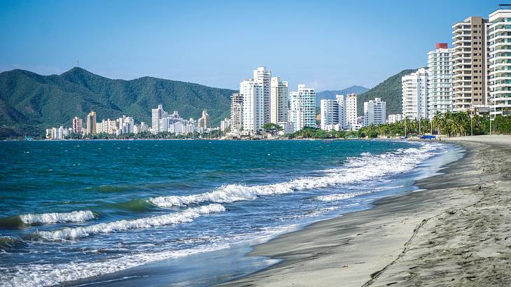 A beach near skyscrapers and mountains