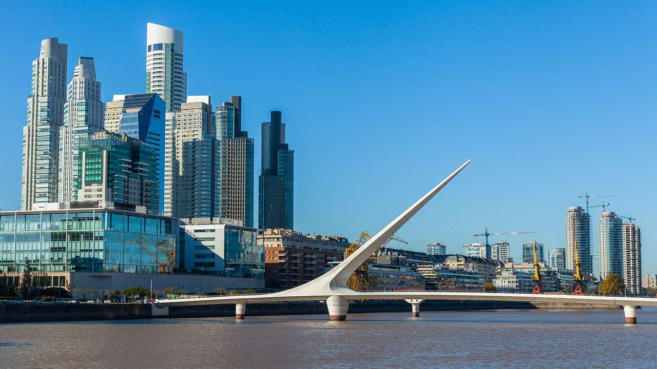 Tall skyscrapers and a modernist bridge by a body of water