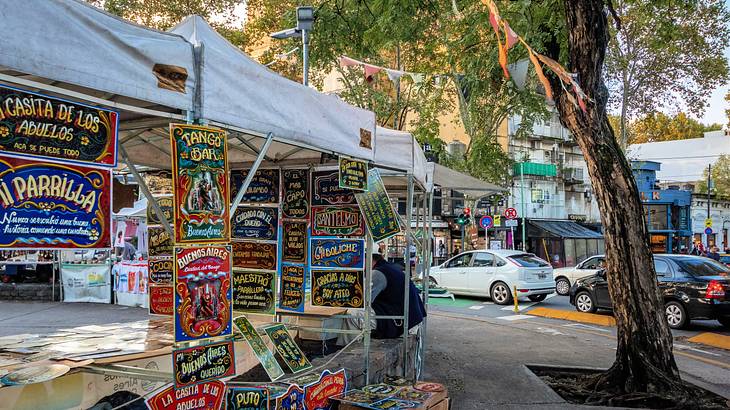 A canopy stall selling artsy items near a road with cars