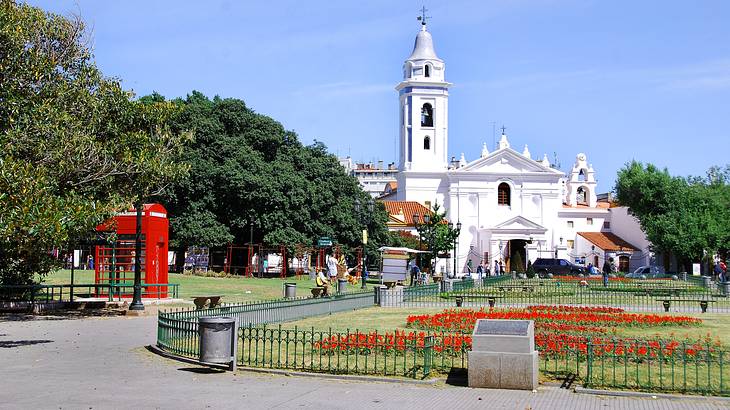 A white church with a pathway and a fenced garden in front