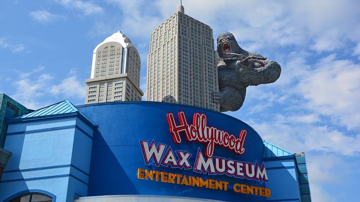 A building with a "Hollywood Wax Museum" sign and a sculpture of a gorilla on top