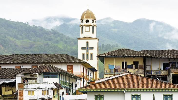 Houses and a cathedral on a hill near the mountains under a cloudy sky