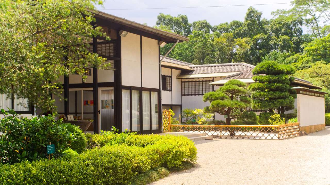 A Japanese-style building next to lots of greenery and a path