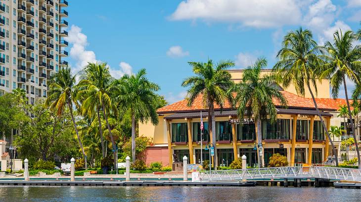 A beachside structure next to water and palm trees on a clear day