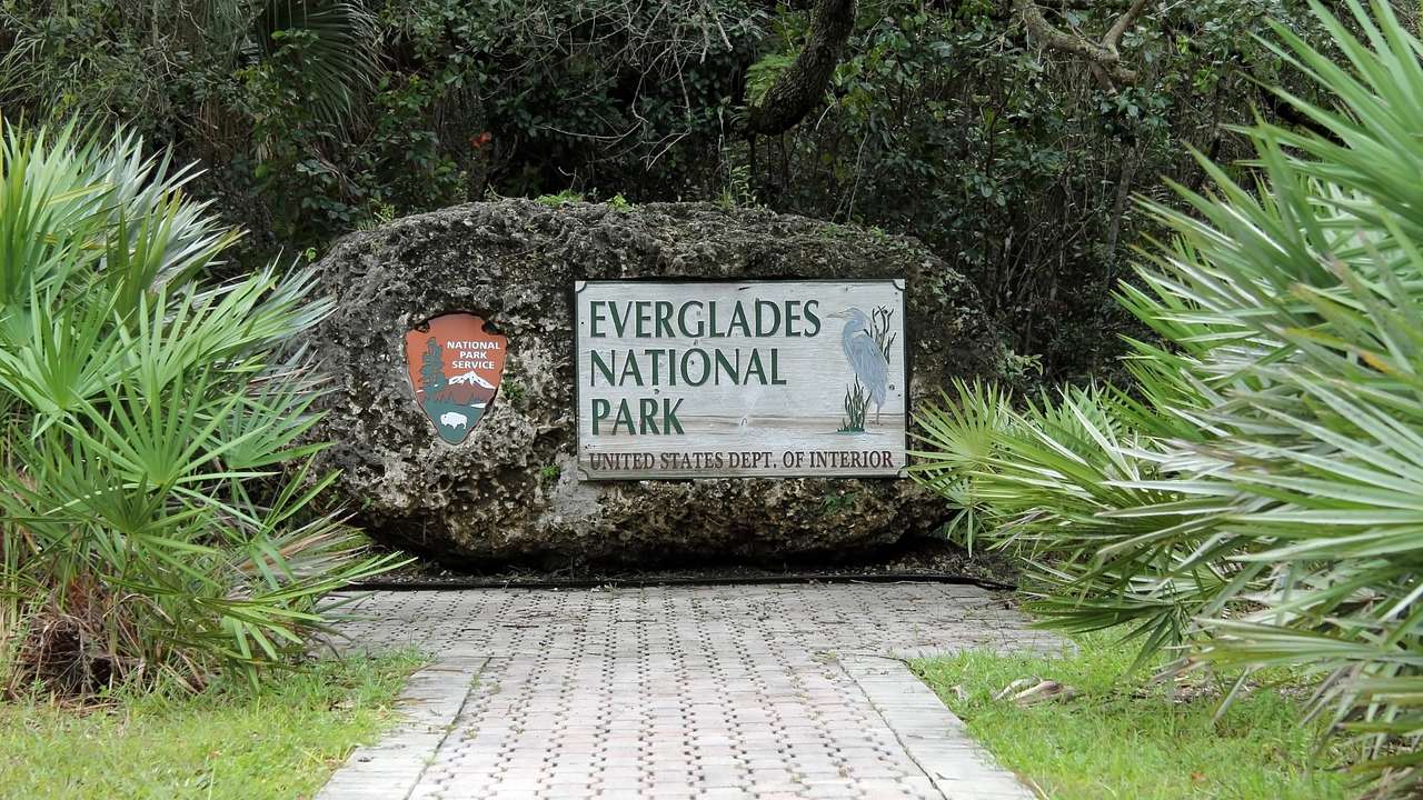 A sign that says "Everglades National Park" next to a path surrounded by greenery