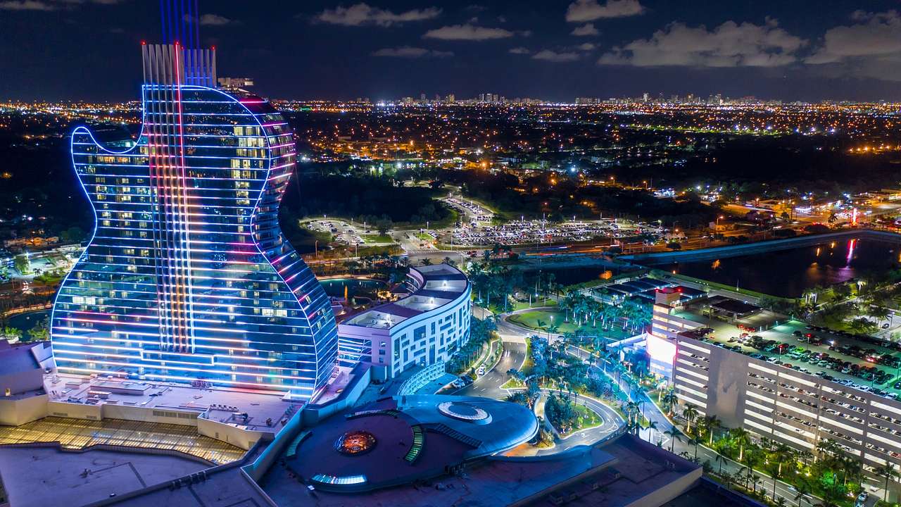The Hard Rock Hotel at night with an illuminated guitar structure and pools