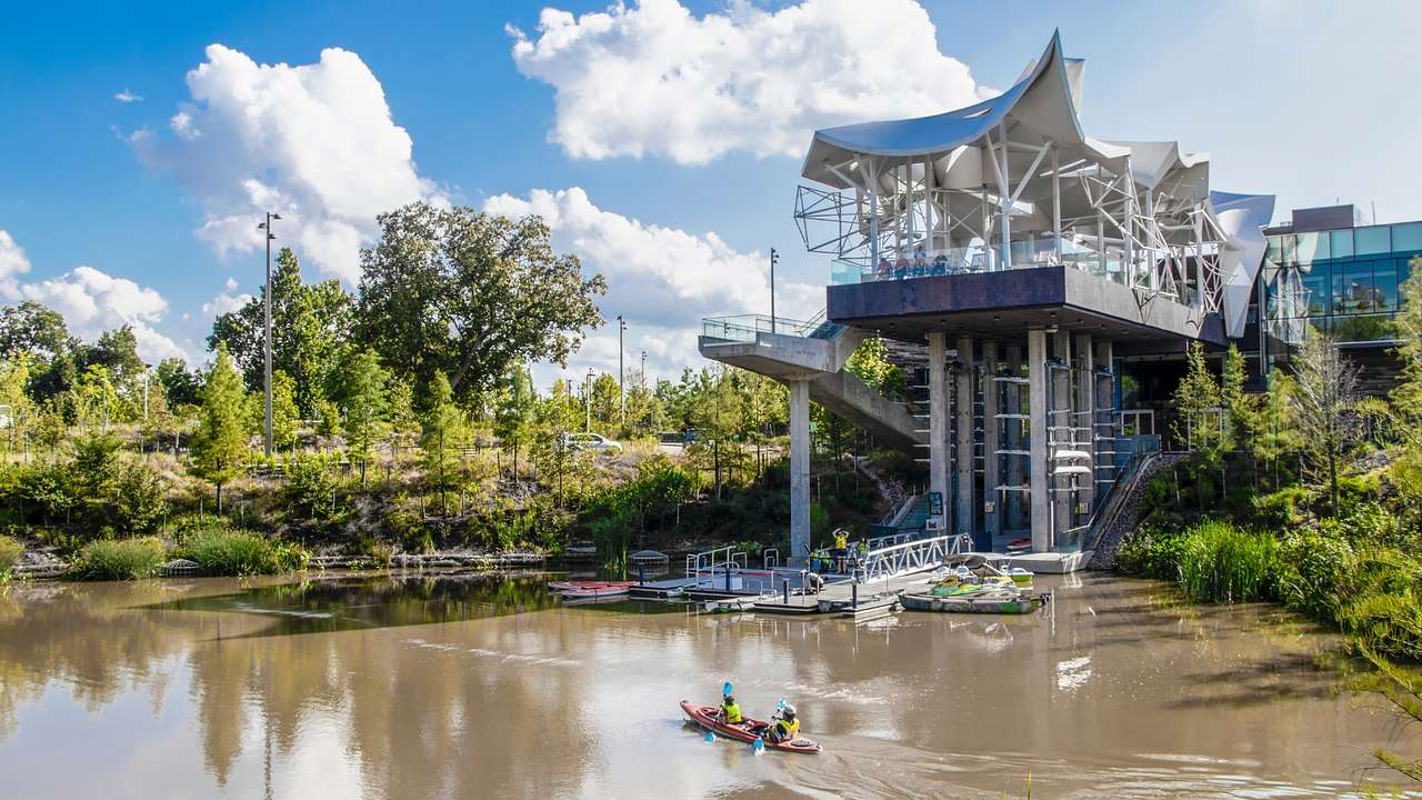 A lake with a kayak on it next to trees and a unique metal structure