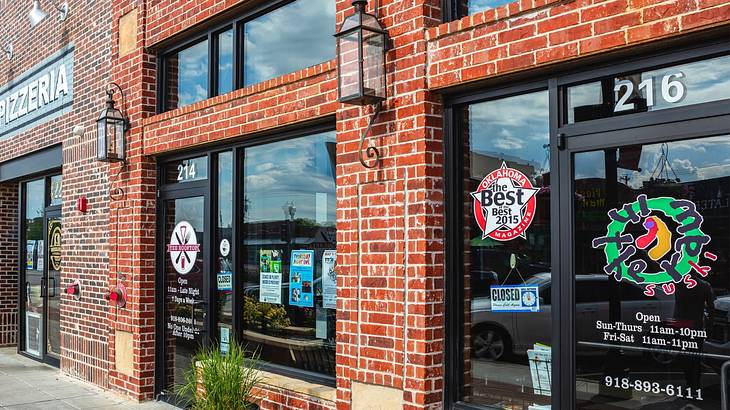 A red brick building with glass windows and doors and an "In the Raw Sushi" sign A red brick building with glass windows and doors and an "In the Raw Sushi" sign