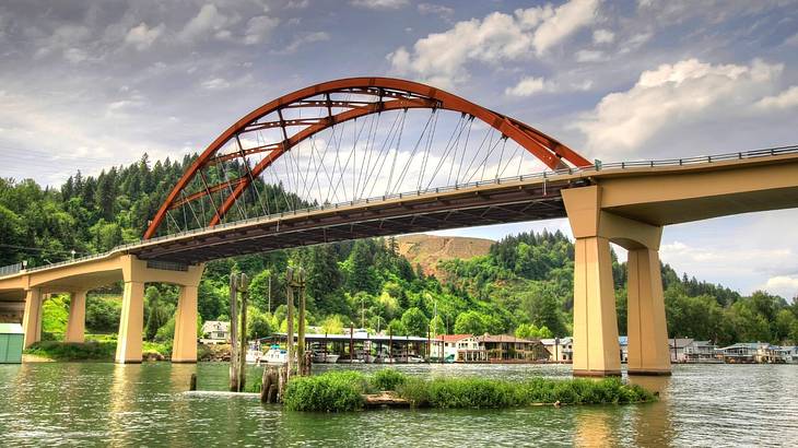 Looking towards a bridge over water against a green hill under a partly cloudy sky Looking towards a bridge over water against a green hill under a partly cloudy sky